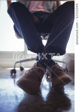 Low section of businessman sitting on chair at office Low section of businessman sitting on chair at office 32332049