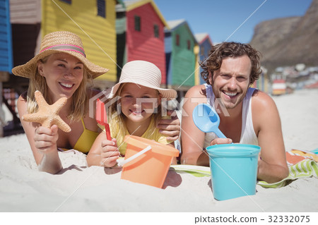 Portrait of happy family lying on blanket at beach 32332075