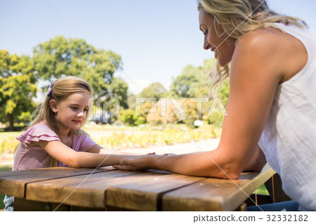 Mother and daughter holding hands on picnic table 32332182
