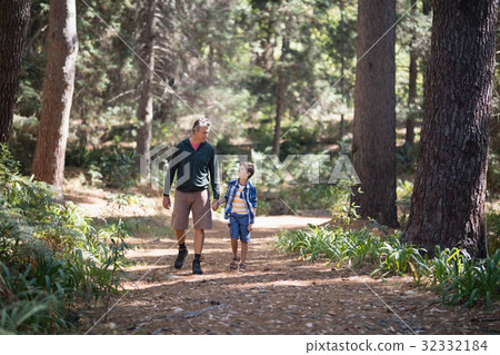 Father and son walking amidst trees in forest Father and son walking amidst trees in forest 32332184