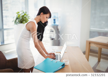 Attentive executive using laptop at desk 32332201