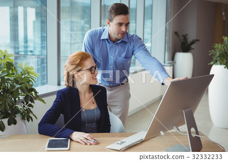 Executives having discussion over personal computer at desk 32332233