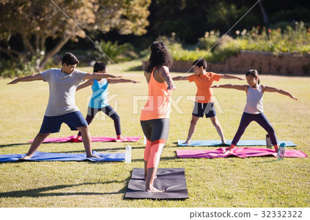 Instructor teaching kids Virabhadrasana II on mat Instructor teaching kids Virabhadrasana II on mat 32332322
