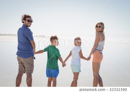Portrait of family holding hands while standing on shore 32332390