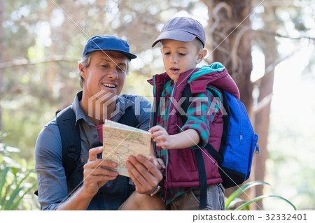 Man and boy reading map in forest Man and boy reading map in forest 32332401