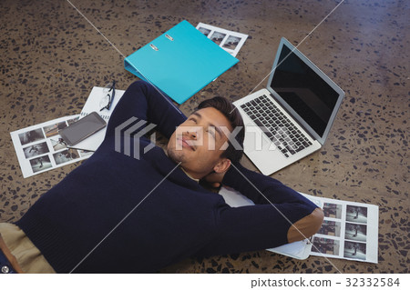Thoughtful businessman lying by laptop and photographs at office 32332584
