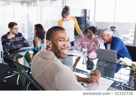 Smiling businessman sitting in meeting Smiling businessman sitting in meeting 32332738