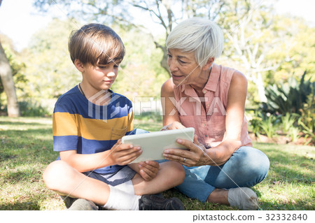 Grandmother and grandson using digital tablet in the park Grandmother and grandson using digital tablet in the park 32332840