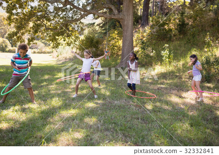 Group of friends playing with hula hoops at campsite Group of friends playing with hula hoops at campsite 32332841