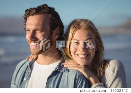 Smiling woman with boyfriend standing at beach Smiling woman with boyfriend standing at beach 32332842