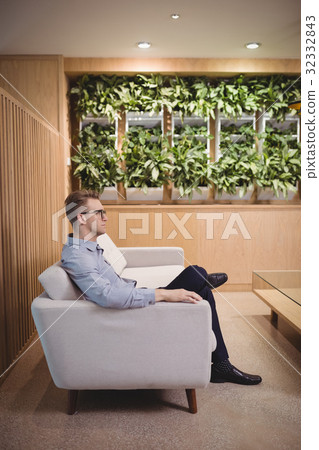 Thoughtful executive sitting on sofa in lobby Thoughtful executive sitting on sofa in lobby 32332843