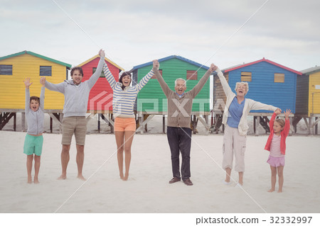 Portrait of cheerful multi-generation family holding hands at beach 32332997