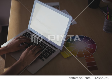 Entrepreneur typing on laptop at office desk Entrepreneur typing on laptop at office desk 32333060