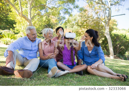 Girl using vr headset while sitting with her family Girl using vr headset while sitting with her family 32333066