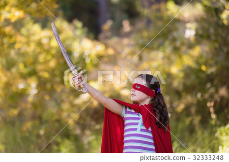 Little girl holding sword while wearing superhero costume Little girl holding sword while wearing superhero costume 32333248