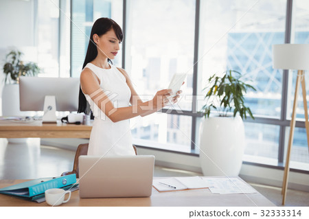 Attentive executive using digital tablet at desk 32333314