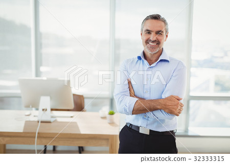 Portrait of smiling executive standing with arms crossed 32333315