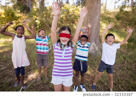 Friends with blindfolded girl cheering in forest Friends with blindfolded girl cheering in forest 32333387