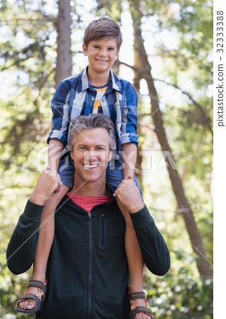 Happy father piggybacking son in forest Happy father piggybacking son in forest 32333388