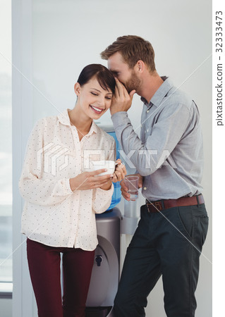 Man whispering in his colleagues ear 32333473