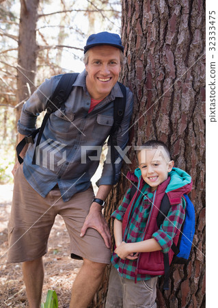 Portrait of happy father and son leaning on tree trunk Portrait of happy father and son leaning on tree trunk 32333475