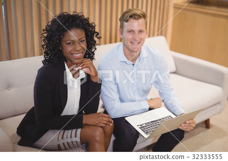 Portrait smiling executives sitting with laptop on sofa 32333555