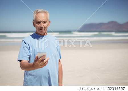 Senior man holding mobile phone at beach Senior man holding mobile phone at beach 32333567