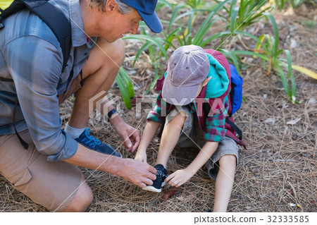 High angle view of man tying shoelace of son High angle view of man tying shoelace of son 32333585