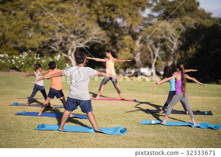 Female trainer teaching children stretching exercise Female trainer teaching children stretching exercise 32333671