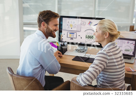 Smiling executives interacting at desk Smiling executives interacting at desk 32333685