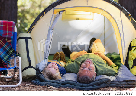 Smiling father and son lying in tent at campsite 32333688
