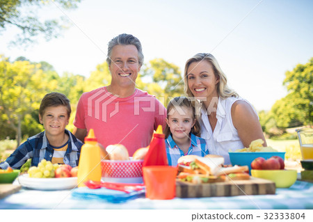 Portrait of happy family having meal in park 32333804