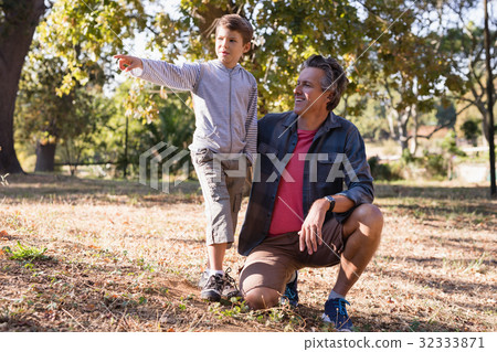 Happy man looking at boy pointing away in forest Happy man looking at boy pointing away in forest 32333871
