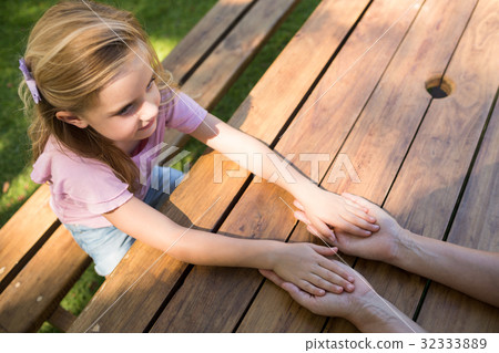 Mother and daughter holding hands on picnic table 32333889
