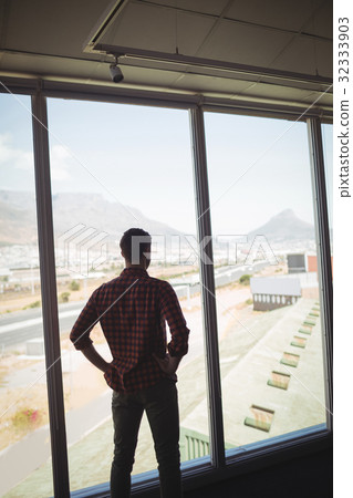Businessman looking through glass window in office Businessman looking through glass window in office 32333903