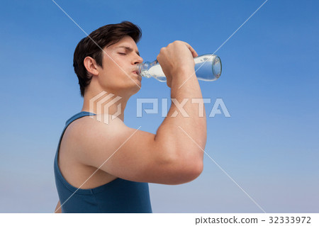 Man drinking water from bottle at beach 32333972