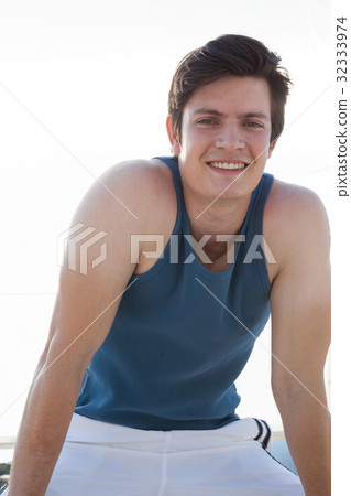 Smiling man taking break after jogging on beach 32333974