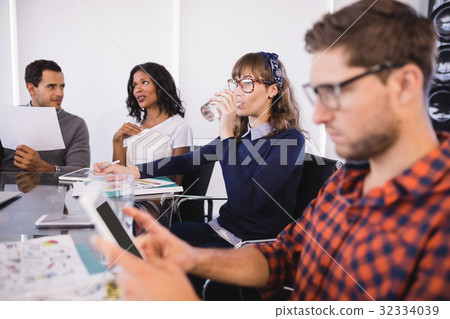 Businesswoman drinking water while sitting with colleagues 32334039