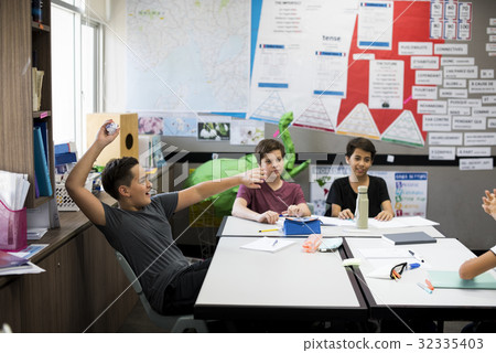 Young boy throwing paper ball in classroom Young boy throwing paper ball in classroom 32335403
