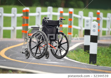 Empty wheelchair across the road in park 32344539