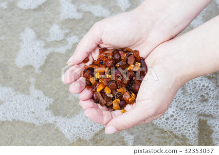 Amber in the hand with a bright reflection on the Amber in the hand with a bright reflection on the 32353037