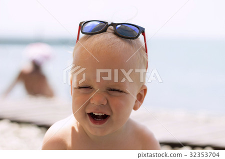 Funny laughing toddler in sunglasses on the sea 32353704