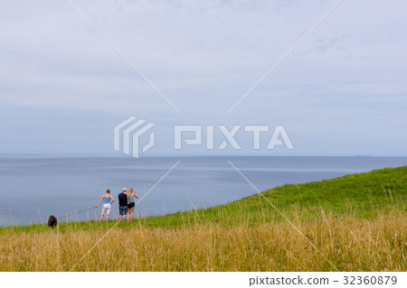 Boy sitting on te edge of a scarp, above the sea 32360879