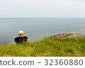 Boy sitting on te edge of a scarp, above the sea 32360880