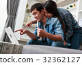 Happy couple online shopping at home 32362127