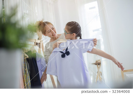 Asian mother helping daughter dressing uniform Asian mother helping daughter dressing uniform 32364008