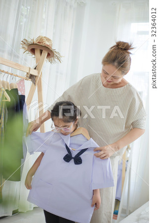 Asian mother helping daughter dressing uniform Asian mother helping daughter dressing uniform 32364012