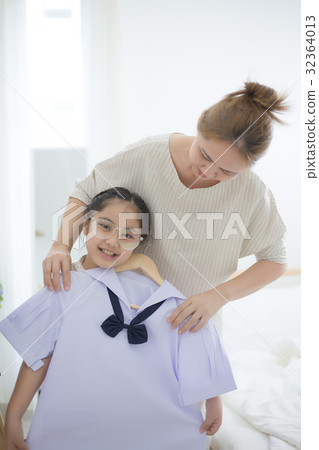 Asian mother helping daughter dressing uniform Asian mother helping daughter dressing uniform 32364013
