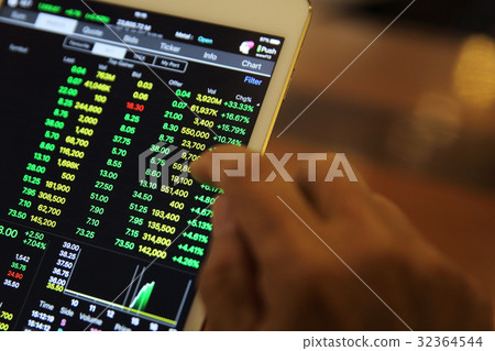A hand Trading online on tablet with business paper and coffee A hand Trading online on tablet with business paper and coffee 32364544