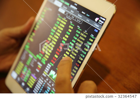 A hand Trading online on tablet with business paper and coffee 32364547